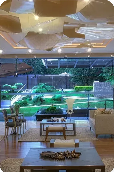 Vista interior de una sala de estar moderna con acceso a un jardín, destacando el diseño y la conexión con esp